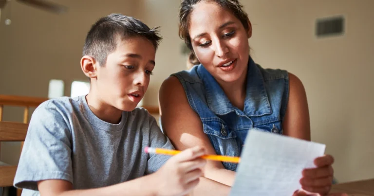 Parent guiding elementary student through focused writing work during homeschool lesson