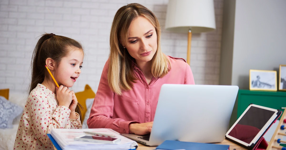 Parent reviewing homeschool curriculum options with child at organized workspace