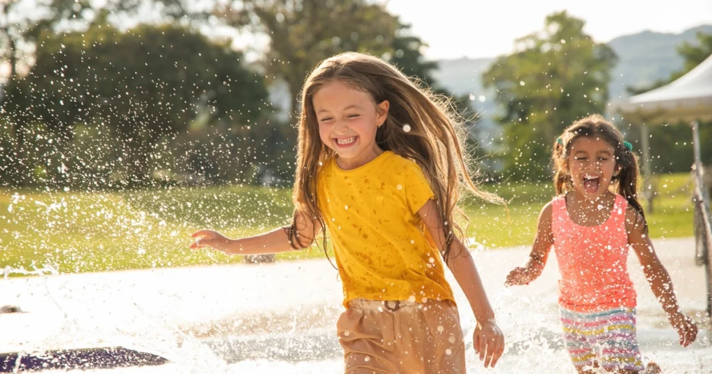 Children playing together at a splash pad during summer, showing how homeschoolers socialize through community activities