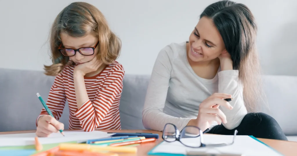 Parent helping a child with a writing assignment during a homeschool lesson at home.