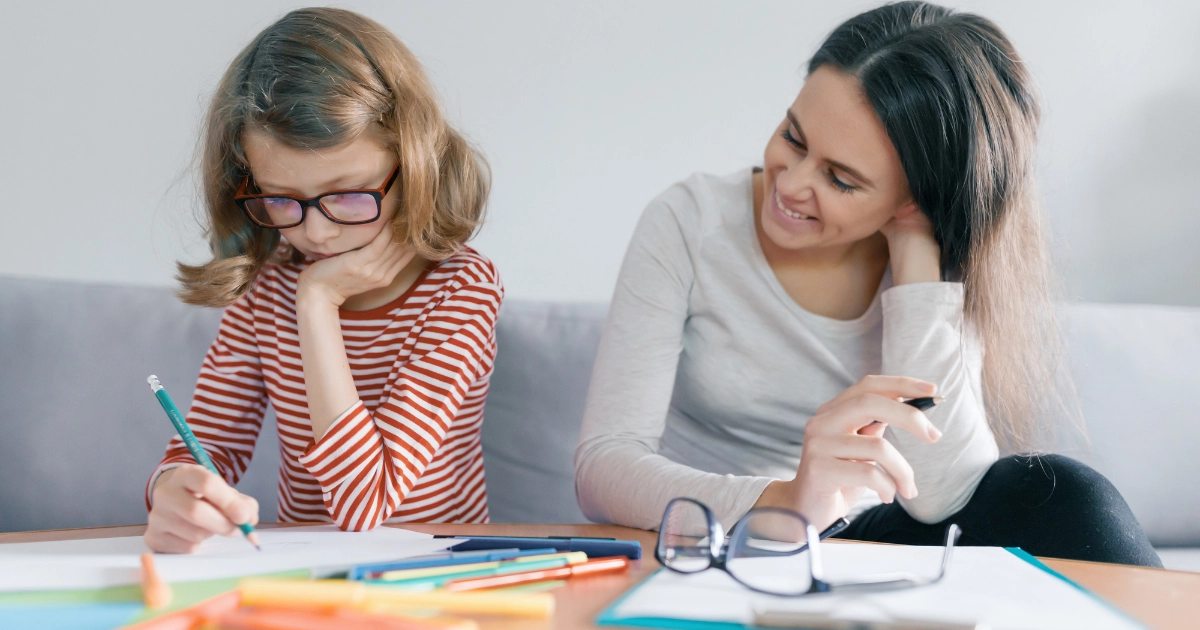 Parent helping a child with a writing assignment during a homeschool lesson at home.