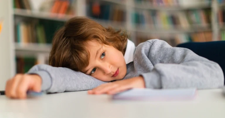 Tired child disengaged from schoolwork while sitting at a desk