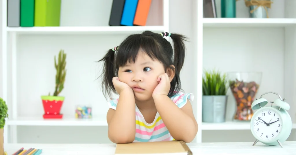 Young homeschool child sitting at a desk looking unsure what to study during a child-led learning session.