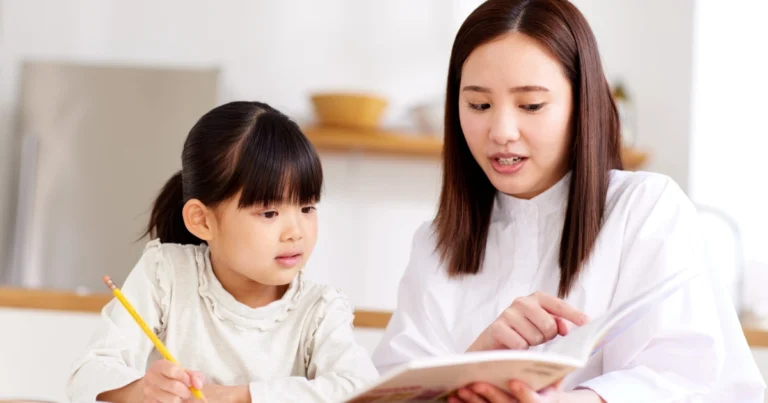 Parent helping a child with reading and schoolwork during a homeschool lesson at home.