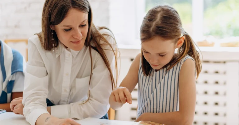 Parent guiding an elementary-age child through a homeschool lesson while reviewing a worksheet together.